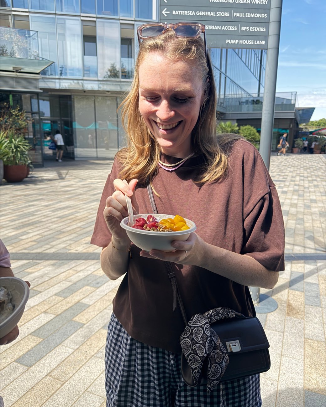 A customer eating her bowl by the market