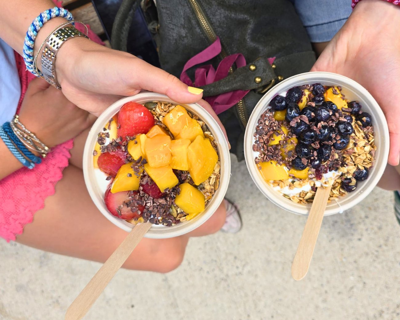 Two finished bowls held up outside the market